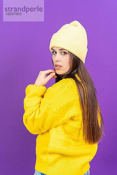Close up Porträt der jungen kaukasischen Frau in Wollpullover vor gelben Studio Hintergrund