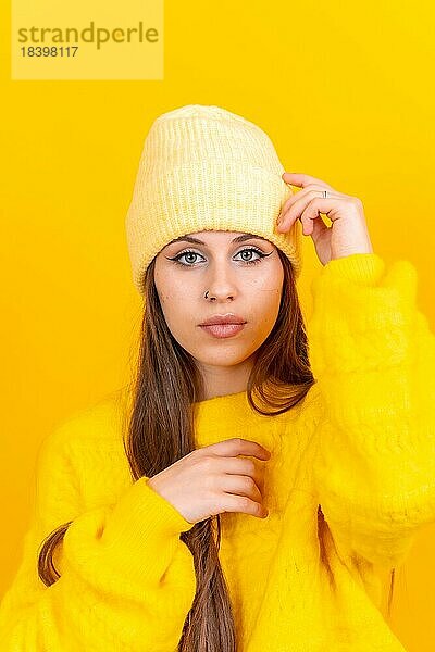 Close up Porträt einer jungen kaukasischen Frau in Wollpullover isoliert über gelben Hintergrund  Blick in die Kamera