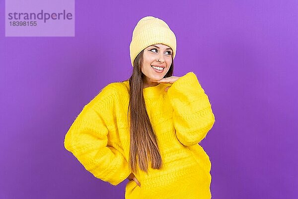 Close up Porträt einer jungen  fröhlichen Frau vorlila Studio Hintergrund in gelben Wollpullover