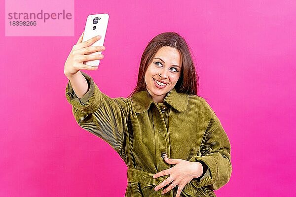 Isolierte Aufnahme einer kaukasischen Frau  die eine Smartphoneapp benutzt und sich an einem Selfie erfreut
