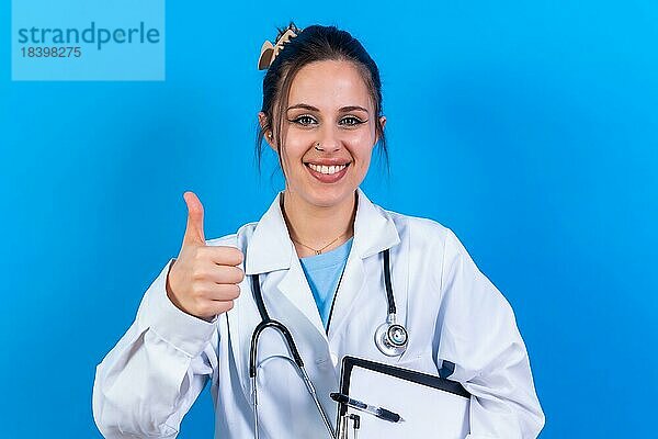 Porträt einer lächelnden Ärztin in medizinischem Kittel  vorblauem Grund  Medizin Konzept  Geste in Ordnung