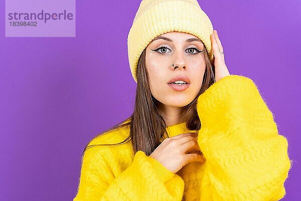 Close up Porträt der jungen kaukasischen Frau in gelben Wollpullover vor gelbem Hintergrund  Blick in die Kamera