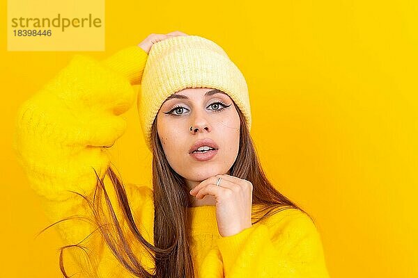 Close up Porträt einer jungen kaukasischen Frau in Wollpullover isoliert über gelben Hintergrund  Blick in die Kamera