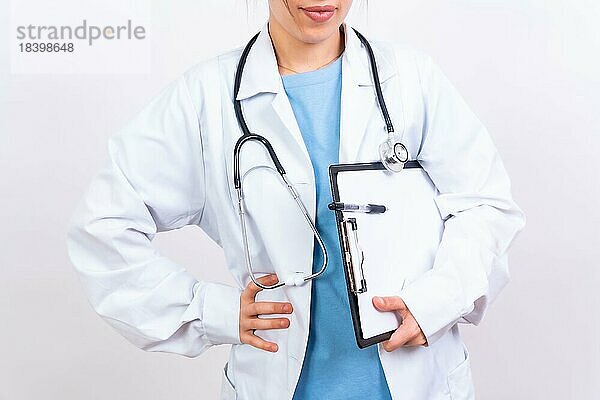Glückliche schöne Ärztin in medizinischem Kittel stehend vor weißem Hintergrund  Medizin Konzept