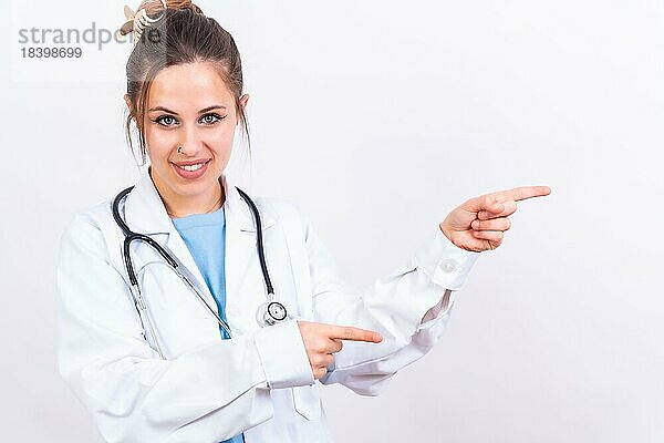 Porträt einer lächelnden Ärztin in medizinischem Kittel  vor weißem Hintergrundem Untergrund  Medizin Konzept  zeigend