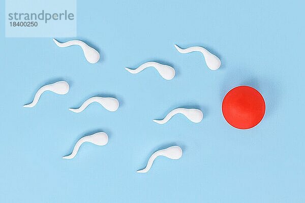 Abstrakte Spermien schwimmen in Richtung Eizelle auf blauem Hintergrund