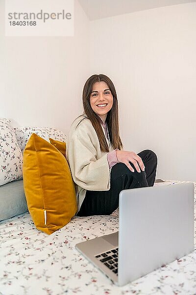 Porträt einer Frau  die mit einem Laptop auf dem Bett arbeitet  Telearbeit