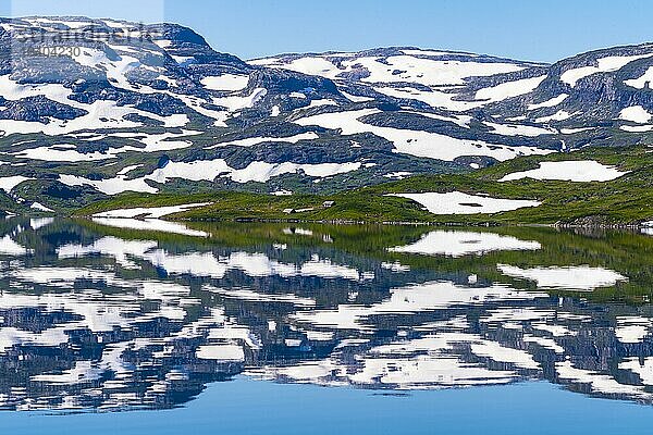 Spiegelung teilweise schneebedeckter Berge im See Stavatn im Haukelifjell  Hardangervidda  Norwegen  Europa
