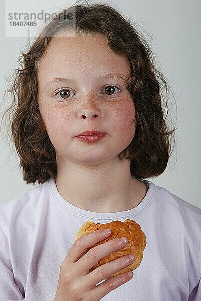 Ein junges Mädchen isst ein Brötchen