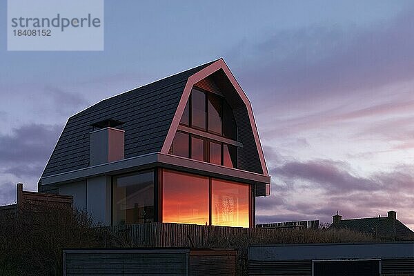 Modernes Ferienhaus  Sonnenuntergang spiegelt sich im Fenster  holländische Nordseeküste  Bergen aan Zee  Provinz Nordholland  Niederlande  Europa