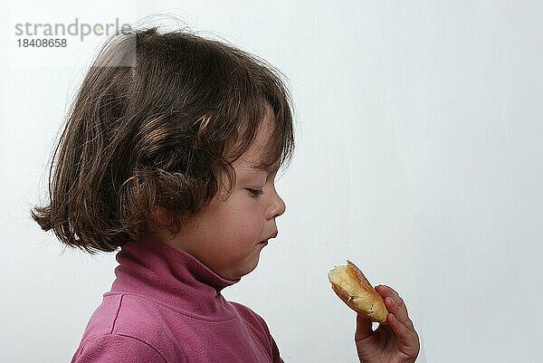 Ein junges Mädchen isst ein Brötchen