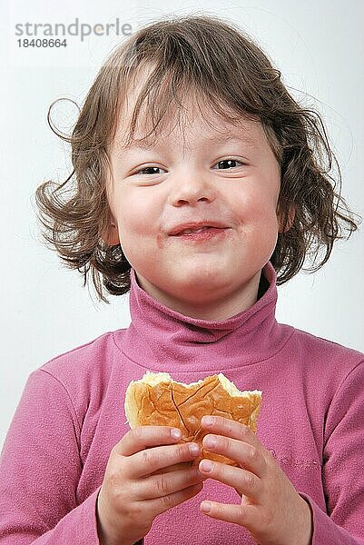 Ein junges Mädchen isst ein Brötchen