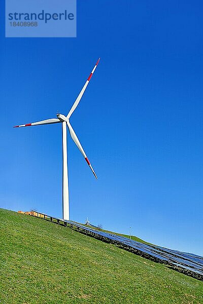 Erneuerbare Wind und Sonnenenergie. Windturbine neben einer Photovoltaikanlage auf einem Hügel