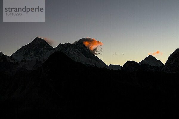 Tagesanbruch am Gokyo Ri. Drei Wolken markieren drei Achttausender  den Mount Everest links  den Lhotse in der Mitte und den Makalu auf der rechten Seite in größerer Entfernung. Silhouette der Bergkämme. Gokyo Trek  Khumbu  Everest Region  Himalaya. Sagarmatha Nationalpark  ein UNESCO Weltnaturerbe. Solukhumbu  Nepal  Asien