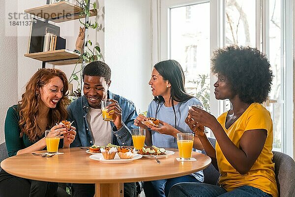 Freunde bei einem Frühstück mit Orangensaft und Muffins zu Hause  die Spaß am Morgen haben