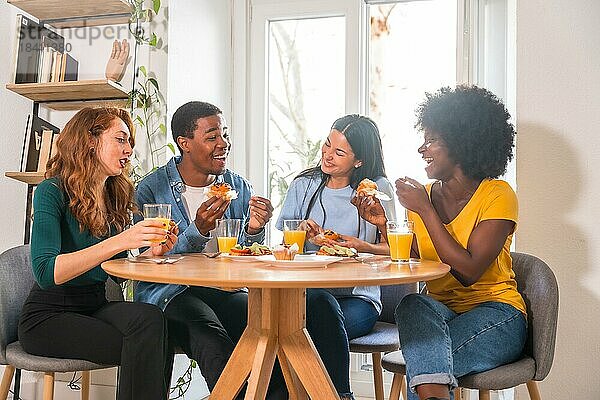 Freunde bei einem Frühstück mit Orangensaft und Muffins zu Hause  die Spaß am häuslichen Leben haben