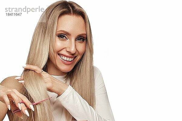 Schöne blonde Mädchen mit einem perfekt Haar  und klassische Make up mit Schere in der Hand. Schönheit Gesicht und Haar. Bild im Studio aufgenommen