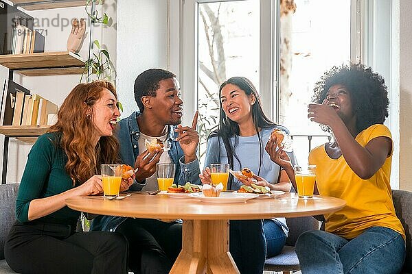 Freunde bei einem Frühstück mit Orangensaft und Muffins zu Hause  um gemeinsam gute Nachrichten zu feiern