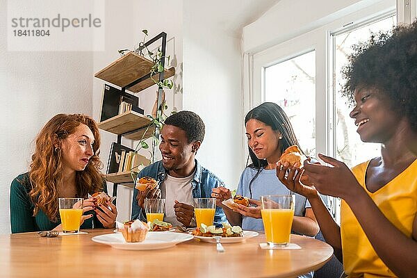 Freunde bei einem Frühstück mit Orangensaft und Muffins zu Hause  entspannt bei heimischen Speisen und Getränken