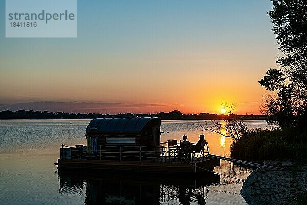 Zwei Männer sitzen bei Sonnenuntergang auf einem Hausboot  Hausfloß  vor der Insel Kiehnwerder  Breitlingsee  Brandenburg an der Havel  Havelland  Brandenburg  Deutschland  Europa
