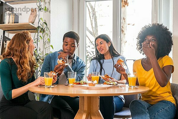 Freunde bei einem Frühstück mit Orangensaft und Muffins zu Hause  die Spaß am häuslichen Leben haben