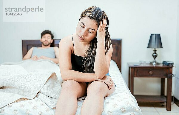 Frau auf dem Rand des Bettes streitet mit ihrem Mann. Aufgeregte Frau  die sich mit ihrem Mann im Bett streitet. Konzept der Paar Probleme im Bett