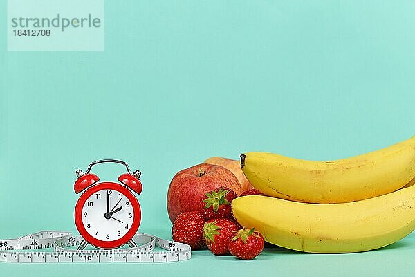 Diätkonzept mit Früchten  Maßband und Uhr auf teal blauen Hintergrund mit Kopie Raum
