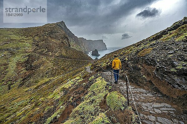 Wanderer auf Wanderweg an der Felszunge  Küstenlandschaft mit roten Steilklippen und Meer  zerklüftete Küste mit Felsformationen  Kap Ponta de São Lourenço  Madeira  Portugal  Europa