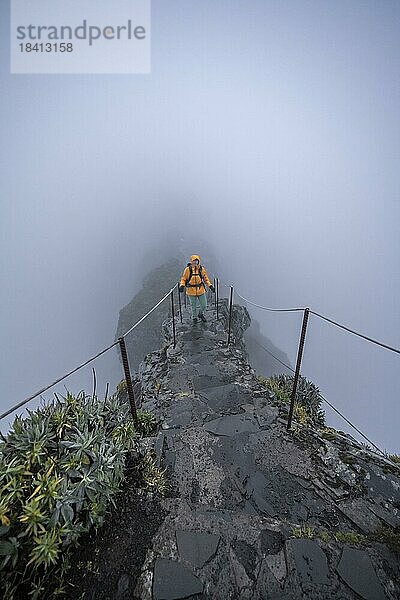 Wanderin an einem schmalen grad im Nebel  Pico Arieiro zum Pico Ruivo Wanderung  Wanderweg an Felsenklippe  Zentralgebirge Madeiras  Madeira  Portugal  Europa