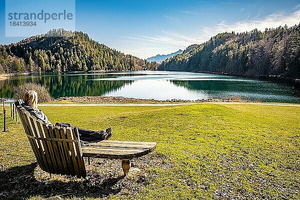 Wander Frau sitzt auf Bank und blickt auf den See  Attlesee  Allgäu  Bayern  Deutschland  Europa