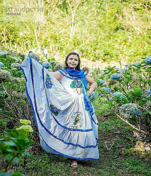 Lächelnde Frau in Volkstracht auf einem von Blumen umgebenen Feld. Menschen in nicaraguanischer Volkstracht. Nicaraguanische Frau in traditioneller Tracht auf einem Feld in Milflores