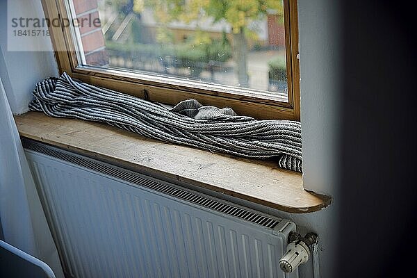 Symbolfoto zum Thema kalte Wohnung. Eine Decke liegt zum Schutz gegen kalte Luft auf der Fensterbank vor einem schlecht isolierten Fenster. Berlin  Berlin  Deutschland  Europa