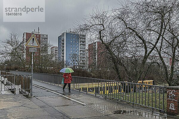 Eine Frau mit buntem Regenschirm zeichnet sich ab vor einem Wohnblock im Bezirk Marzahn  aufgenommen in Berlin  01.02.2023.  Berlin  Deutschland  Europa