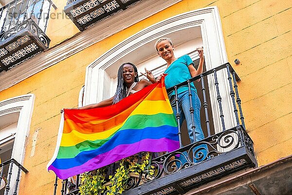 Lesbische Mädchen Paare mit lgbt Flagge auf Balkon zu Hause Partei  winken lächelnd  LGBT Stolz