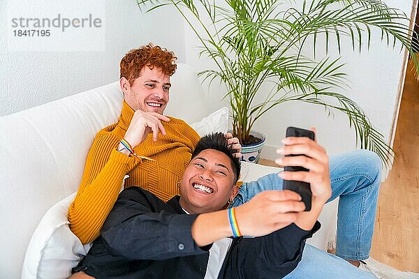 Schönes homosexuelles Paar  das drinnen auf dem Sofa romantisch ist  homosexuelles Paar  das ein Selfie macht