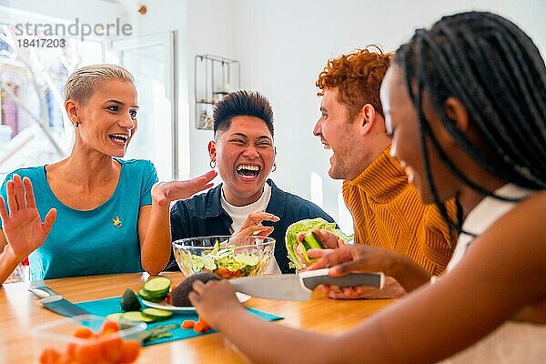 Porträt einer Gruppe von Freunden bei der Zubereitung vegetarischer Gerichte. Sie bereiten den Salat vor und haben Spaß im Haus