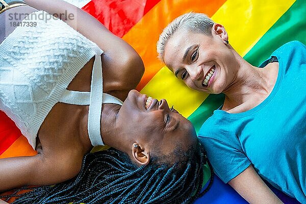 Schöne lesbische Paar über Regenbogenflagge  lgbt Konzept  romantische Pose  lächelnd