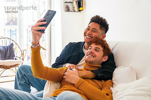 Schöne Homosexuell Paar wird romantisch drinnen zu Hause auf dem Sofa  ein Selfie  lgbt Konzept