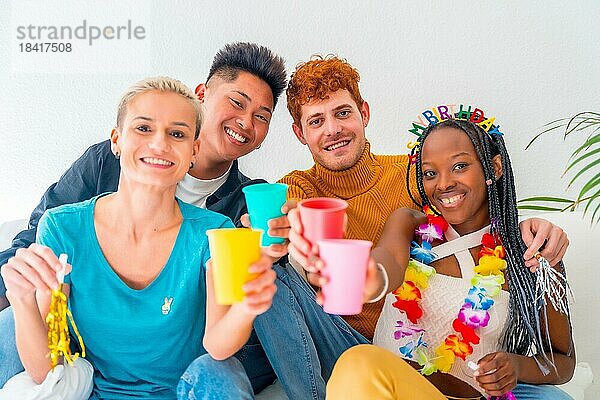 Lgtb Paare von Homosexuell Jungen und Mädchen lesbisch in einem Porträt auf einem Sofa in einem Haus Partei  Geburtstagsfeier  Toast mit farbigen Gläsern