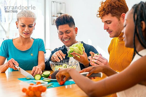 Eine Gruppe von Freunden bereitet ein vegetarisches Essen zu. Den Salat zubereiten und Spaß in der Küche haben