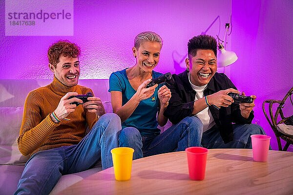 Eine Gruppe junger Freunde spielt zu Hause auf dem Sofa Videospiele  lila angeführt