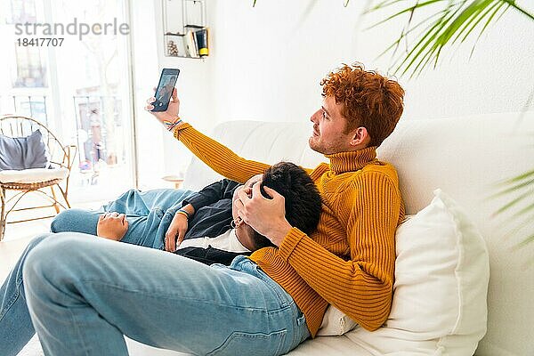 Schöne Homosexuell Paar wird romantisch drinnen zu Hause auf dem Sofa  Homosexuell Paar Selfie  lgbt Konzept