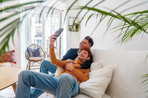 Schönes homosexuelles Paar  das zu Hause auf dem Sofa romantisch ist und ein Selfie macht  lgbt Konzept