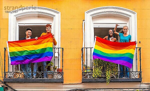 Paare von schwulen Jungen und lesbischen Mädchen mit der lgtb Flagge auf den Balkonen bei einer Hausparty  Begrüßung von Freunden  LGBT Stolz