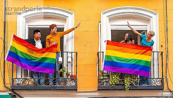 Paare von schwulen Jungen und lesbischen Mädchen mit der lgtb Flagge auf den Balkonen bei einer Hausparty  Begrüßung von Freunden  LGBT Stolz