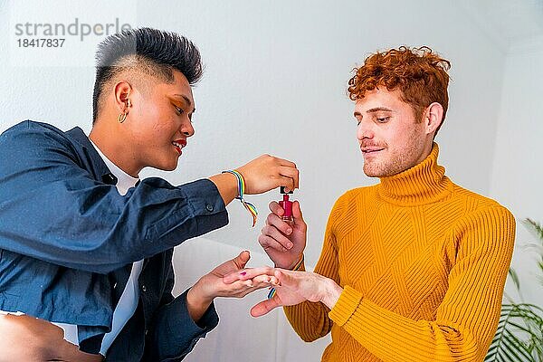 Schöne Homosexuell Paar tun Make up  ihre Nägel zu malen und Spaß haben drinnen zu Hause  lgbt Konzept