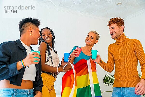 LGBT Stolz  lgbt Regenbogenflagge  Gruppe von Freunden tanzen und stoßen mit Gläsern in einem Haus auf Party