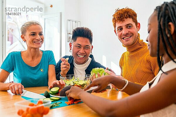Porträt einer Gruppe von Freunden bei der Zubereitung von vegetarischem Essen. Sie bereiten den Salat vor und haben Spaß