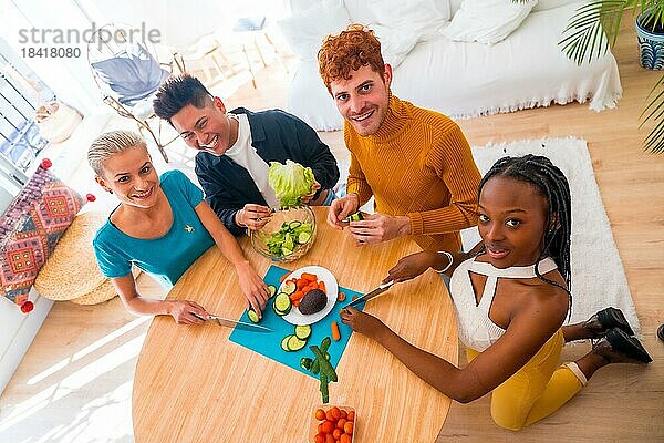 Porträt einer Gruppe von Freunden bei der Zubereitung von vegetarischem Essen. Salat zubereiten und Spaß im Zimmer haben