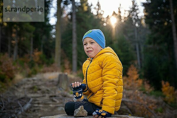 Kleines Kind sitzt auf einem großen Baumstumpf auf dem Bergpfad und isst. Herbstzeit  Polen  Europa